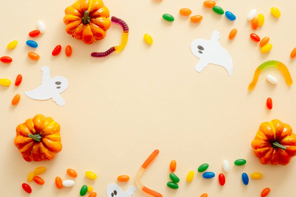 Halloween composition. Halloween decorations, pumpkins, candy on pastel beige background. Halloween concept. Flat lay, top view, copy space - Foto, imagen