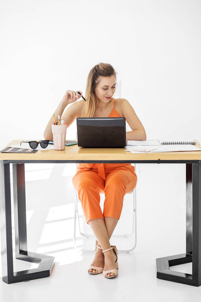 Una joven se sienta en un escritorio de la oficina y trabaja. Concepto para negocios, trabajo, carrera
. - Foto, Imagen