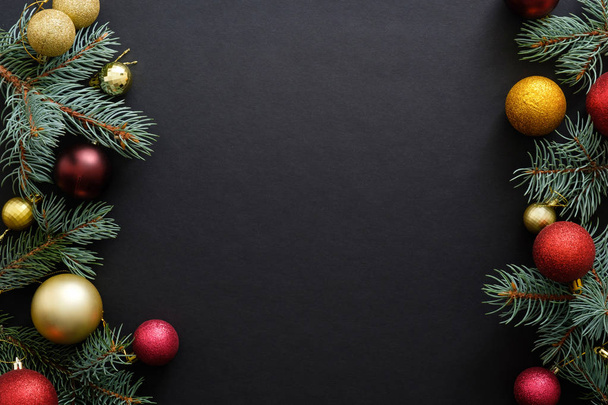 Černé vánoční zázemí s sváteční výzdobou, bafiky, jedle ze stromových větví. Vánoční svátky, zima, koncept nového roku. Vánoční stromeček, šablona přání. - Fotografie, Obrázek