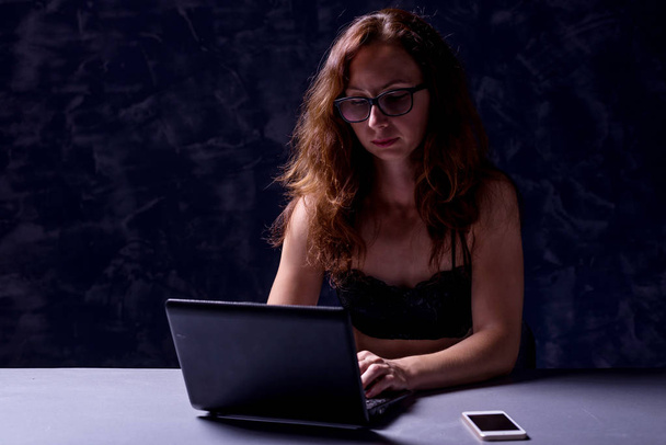 Woman freelancer uses a laptop at night, a workaholic. - Foto, afbeelding