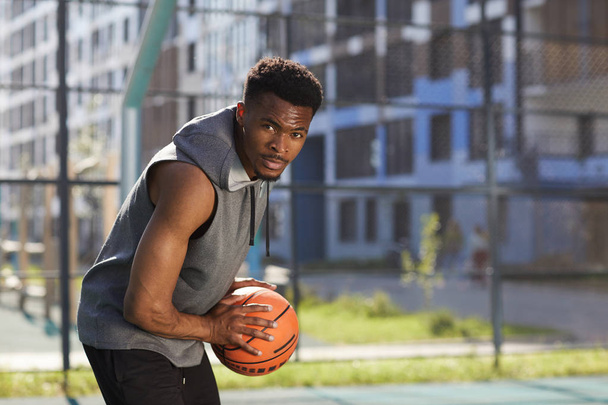 Porträt eines entschlossenen Basketballspielers, der in die Kamera blickt, den Ball hält, Raum kopiert - Foto, Bild