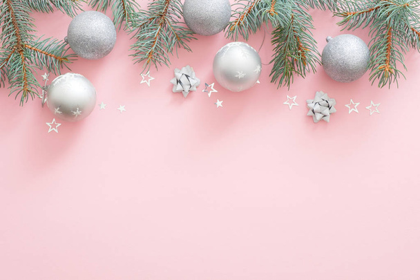 Christmas holiday composition. Christmas tree fir branches, silver balls on top border on pink pastel background with copy space. Flat lay, top view, Xmas glamour banner mockup, invitation card. - Foto, Imagem