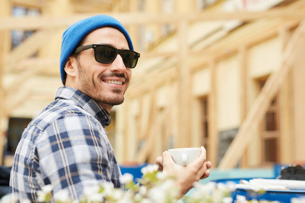 Ritratto di giovane uomo moderno con occhiali da sole che si gode una tazza di caffè mentre viaggia in Europa, copiare lo spazio
 - Foto, immagini