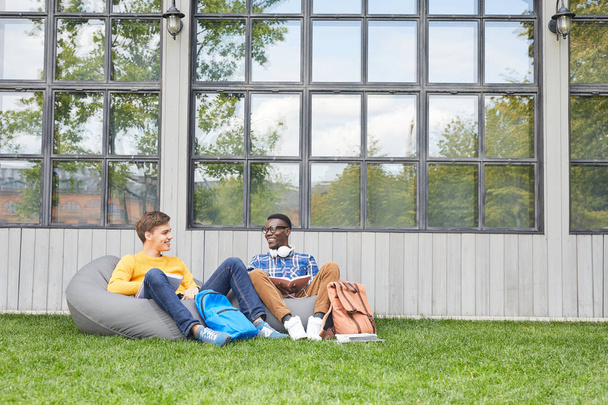 大学キャンパスで屋外でリラックスした2人の学生のフルレングスポート、コピースペース - 写真・画像
