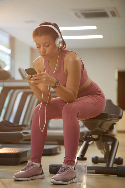 Портрет красивої молодої жінки з використанням смартфона під час перерви в спортзалі, копіювання простору
 - Фото, зображення