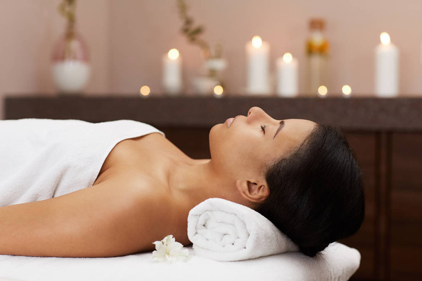 Vista lateral retrato de bela mulher mestiça relaxante em SPA de luxo pronto para massagem, espaço de cópia
 - Foto, Imagem