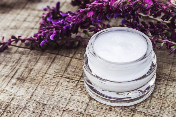 Crème cosmétique dans un pot en verre sur un fond en bois avec des fleurs sauvages de lavande. Crème visage
. - Photo, image