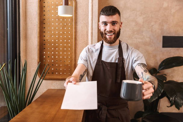 Happy young man barista wearing apron - Фото, изображение