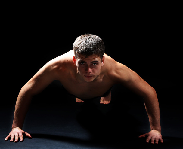 Handsome young muscular sportsman, on dark background - Foto, imagen