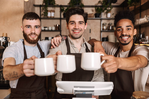 Group of cheerful men baristas wearing aprons - Foto, immagini
