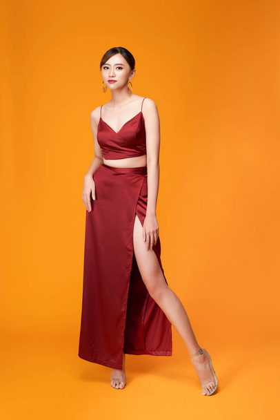 Full length portrait of young sexy woman in red dress  standing and posing against yellow background - Φωτογραφία, εικόνα