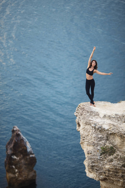 Krásná štíhlá žena trénuje jómu a Pilates na útesu hory s výhledem na moře. Koncepce životního stylu sportivního a heatie. - Fotografie, Obrázek