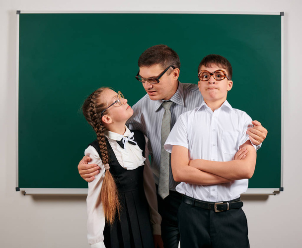 Portrait of a teacher, schoolboy and schoolgirl with old fashioned eyeglasses posing on blackboard background - back to school and education concept - Photo, Image