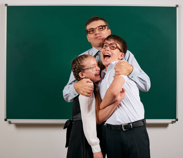 Porträt einer Lehrerin, eines Schülers und einer Schülerin mit altmodischer Brille, die auf Tafelhintergrund posiert - zurück zum Schul- und Bildungskonzept - Foto, Bild