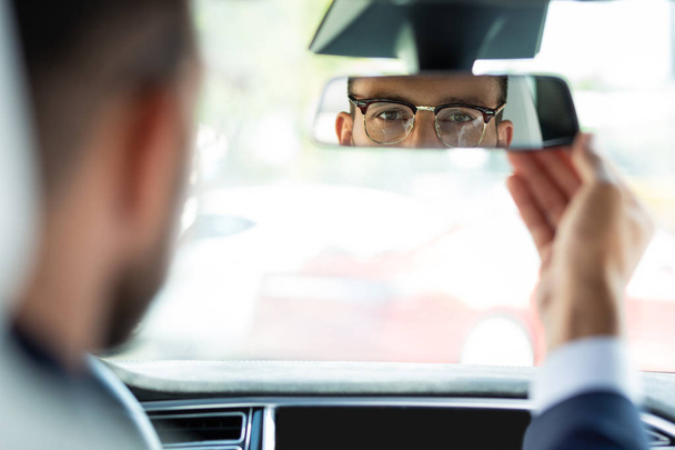 Επιχειρηματίας που φτιάχνει καθρέφτη πίσω όψη πριν από την οδήγηση του αυτοκινήτου του - Φωτογραφία, εικόνα