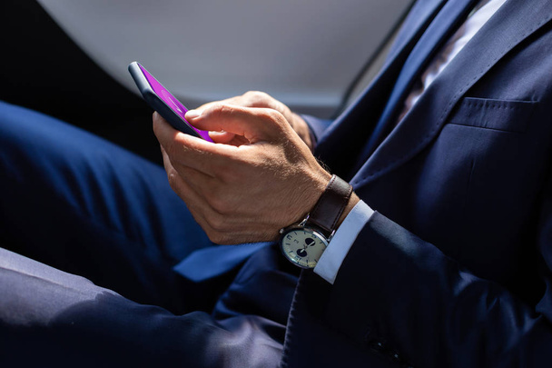 Close up of businessman wearing hand watch texting friend - 写真・画像