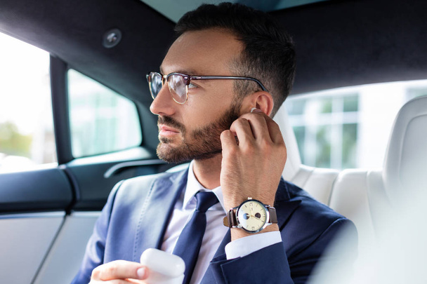Bearded man taking headphones while sitting in his car - 写真・画像