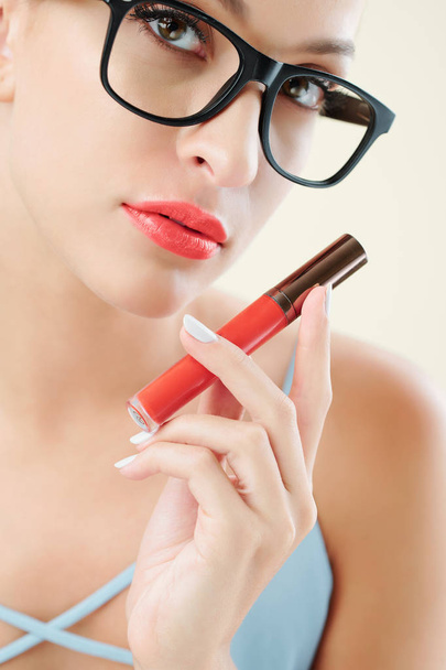 Retrato de jovem com belos lábios cheios mostrando batom líquido vermelho brilhante
 - Foto, Imagem