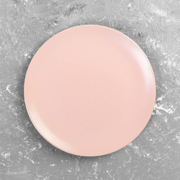 leere rosa oder korallenfarbene runde Platte auf grauem Zementtischhintergrund. Draufsicht, Vorlage für Ihr Design - Foto, Bild