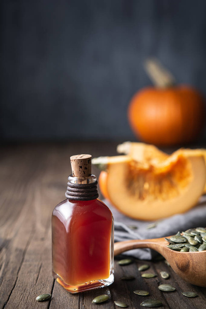 Cold pressed Pumpkin seed oil in a glass bottle, decorated with peeled seeds with copy space - Photo, Image