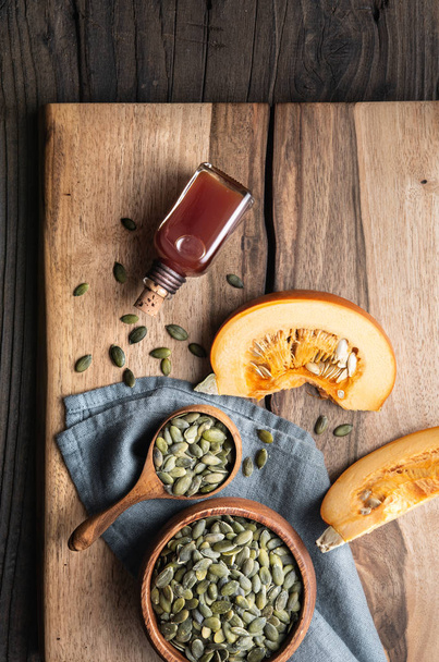 Cold pressed Pumpkin seed oil in a glass bottle, decorated with peeled seeds - Photo, Image