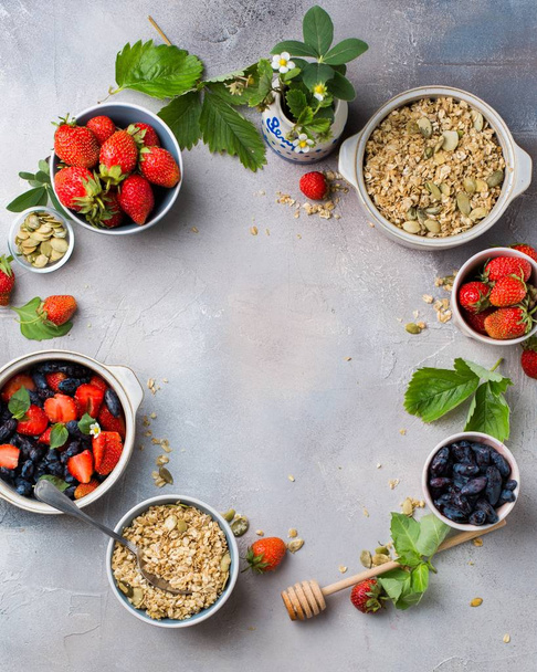 Vertical overhead shot of bowls filled with oats, strawberries and blue fruits - 写真・画像