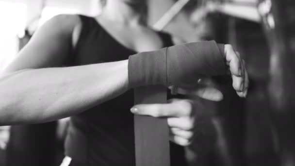 Sportliche Boxerin wickelt rote Gürtel an den Händen, unerschütterliche Schuss.schwarz / weiß - Filmmaterial, Video