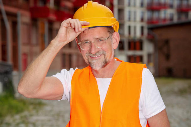 handsome worker in his 50s with helmet standing outside - Фото, изображение