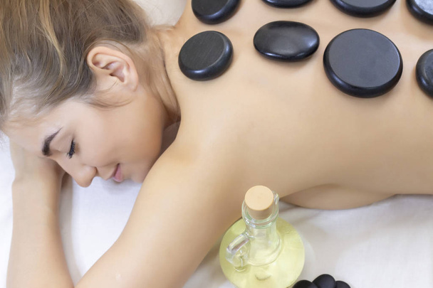 Spa Hot Stone Massage. Stone treatment. Woman getting a hot stone massage at a day spa. beautiful girl - Фото, изображение