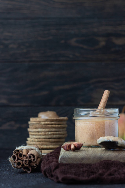 Spicy pear jam in glass jar, crackers, spices (cinnamon and anise) and thyme. Brown stone background. Rustic style. - Fotoğraf, Görsel