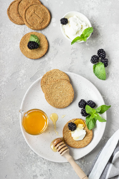 Thin crispy wholegrain crackers with cream cheese, blackberry, grapes, mint and honey.  - Foto, Imagen