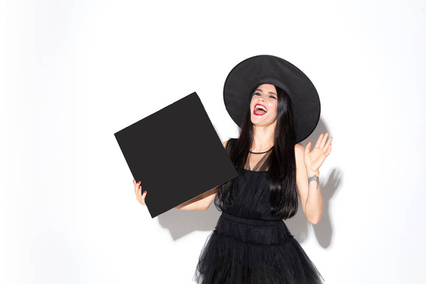 Young woman in hat and dress as a witch on white background - Photo, image
