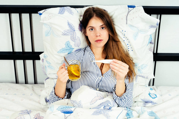 Junge Frau liegt mit Grippesymptomen im Bett - Foto, Bild