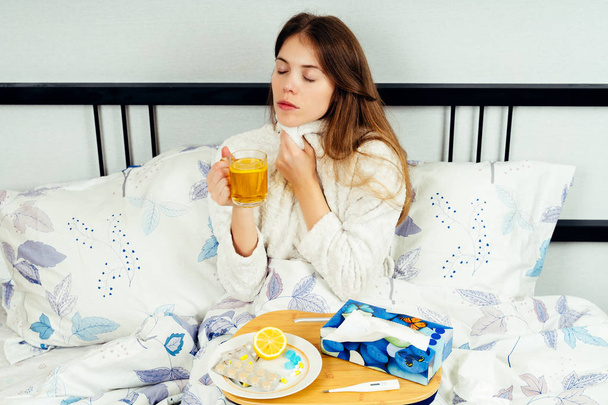 Young woman sitting on the bed with lots of medicine on the bed tabl - Foto, Imagem