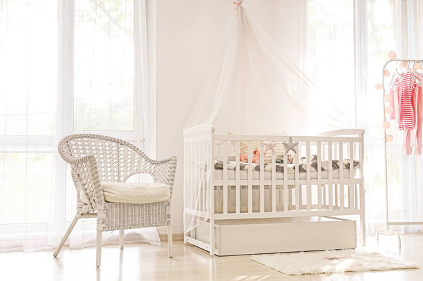 Interior of light modern baby room with crib - Foto, afbeelding