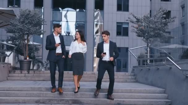 Successful Business People Discuss Business and walk in Central Business District. Two Young Men and one Woman in Suit Communicate and walk near the Office Building of Business Center. - Footage, Video