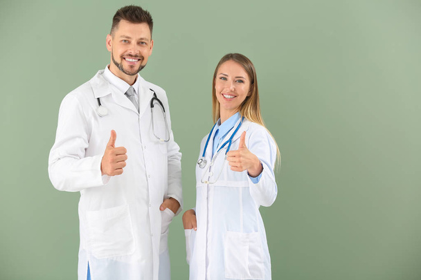 Mężczyzna i kobieta lekarze wykazujący kciuk w górę na kolorowym tle - Zdjęcie, obraz