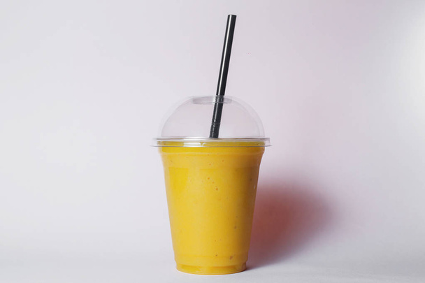 copo descartável de smoothie de frutas trópicas com palha no fundo do estúdio
 - Foto, Imagem