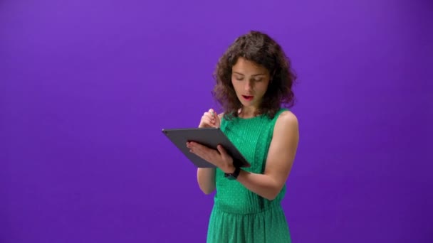 curly girl plays games on an iPhone 11pro in a hand on a purple background - Video, Çekim