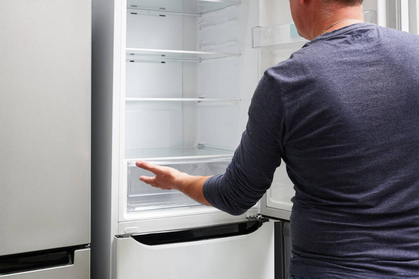 Man looking into empty refrigerator - Valokuva, kuva