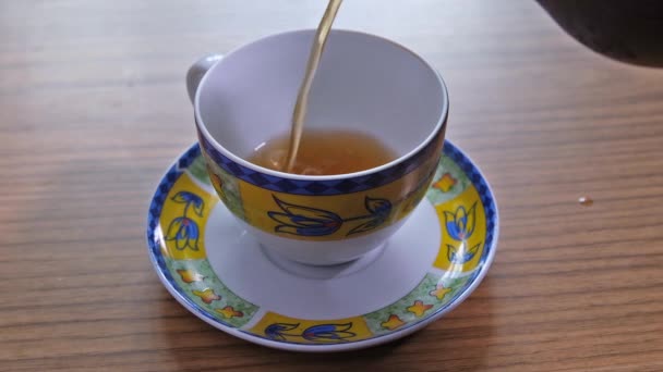 πλάνα από τσάι που χύνεται σε κύπελλο στο τραπέζι - Πλάνα, βίντεο