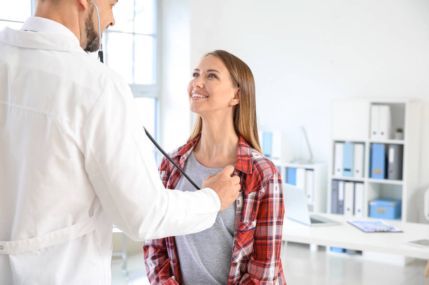 Doctor listening woman's heartbeat in clinic - Photo, image