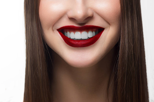Close-up shot of sexy woman lips with red lipstick and white teeth. Perfect clean skin, fashion lip make-up. Beautiful spa portrait with tender pink flower. Spa and cosmetics - Φωτογραφία, εικόνα
