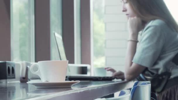 Csésze kávé az asztalra nő dolgozik a laptop a háttérben - Felvétel, videó