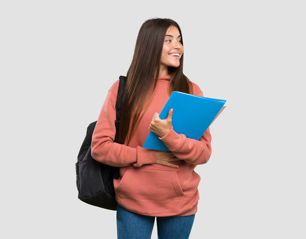 Молодая студентка с блокнотами счастливая и улыбающаяся на изолированном сером фоне
 - Фото, изображение
