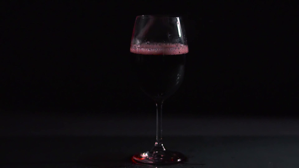 Vörösboros pohár fekete háttérrel, légbuborékok egy pohár borban, videó  - Felvétel, videó