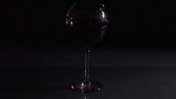 Jégkocka esik egy pohár bor sötét háttér, videó  - Felvétel, videó