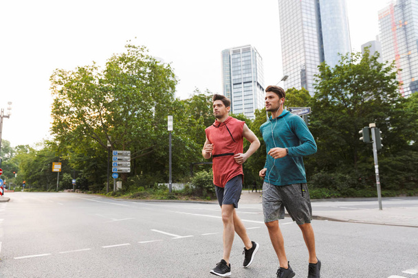 Photo of two athletic young men doing workout and running on city street - Foto, imagen