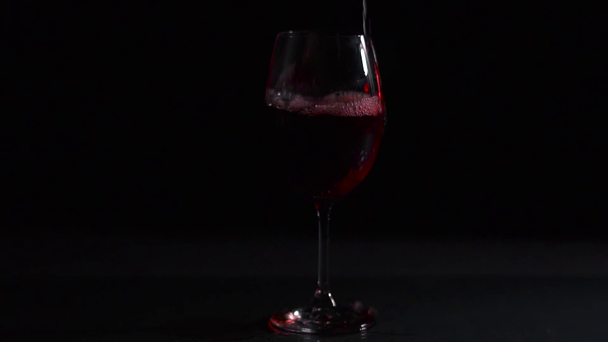 Červené víno nalévá do vína, tmavé pozadí, studio video shot - Záběry, video