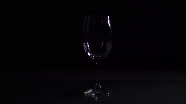 Red wine pours into wine glass, dark background, studio video shot - Footage, Video